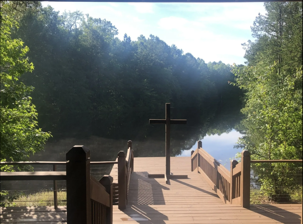 Cross on a dock overlooking a river.